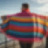 A vibrant surf poncho hanging on a beach railing.